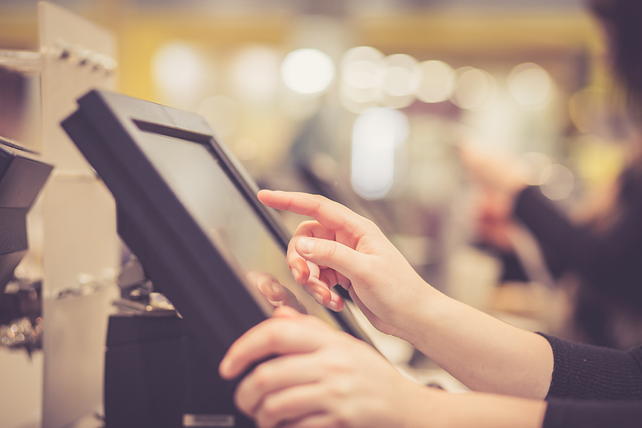 Young woman hands counting / entering discount / sale to a touchscreen cash register, market / shop (color toned image)